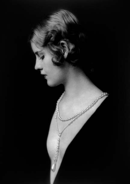 A photo of Caja Eric in fancy dress and a pearl necklace.