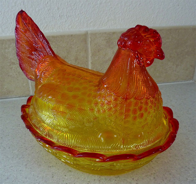Image sample of carnival glass. An orange and yellow gradient of a hen in glass form.
