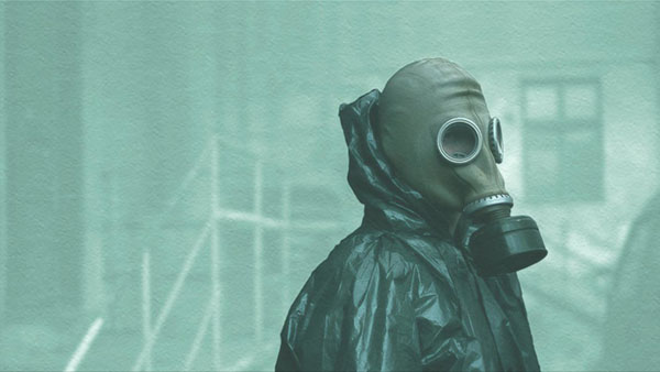 Screen shot of a man in a gas mask with black radiation gear from the show Chernobyl