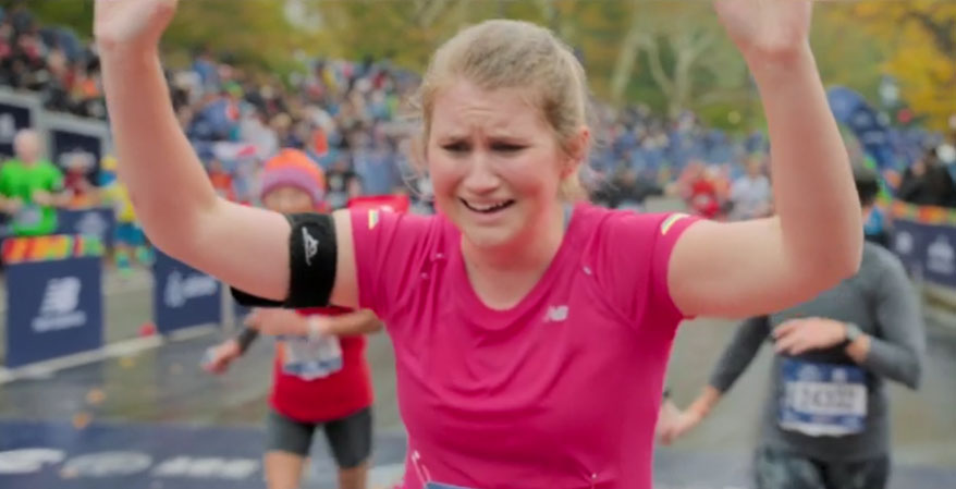 Brittany running at the marathon. Woman in pink runner's gear with hands in the air happy and relieved.