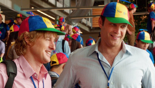 Screenshot of The Internship. Two middle aged men with Google hats enjoy a conversation with someone off-screen.