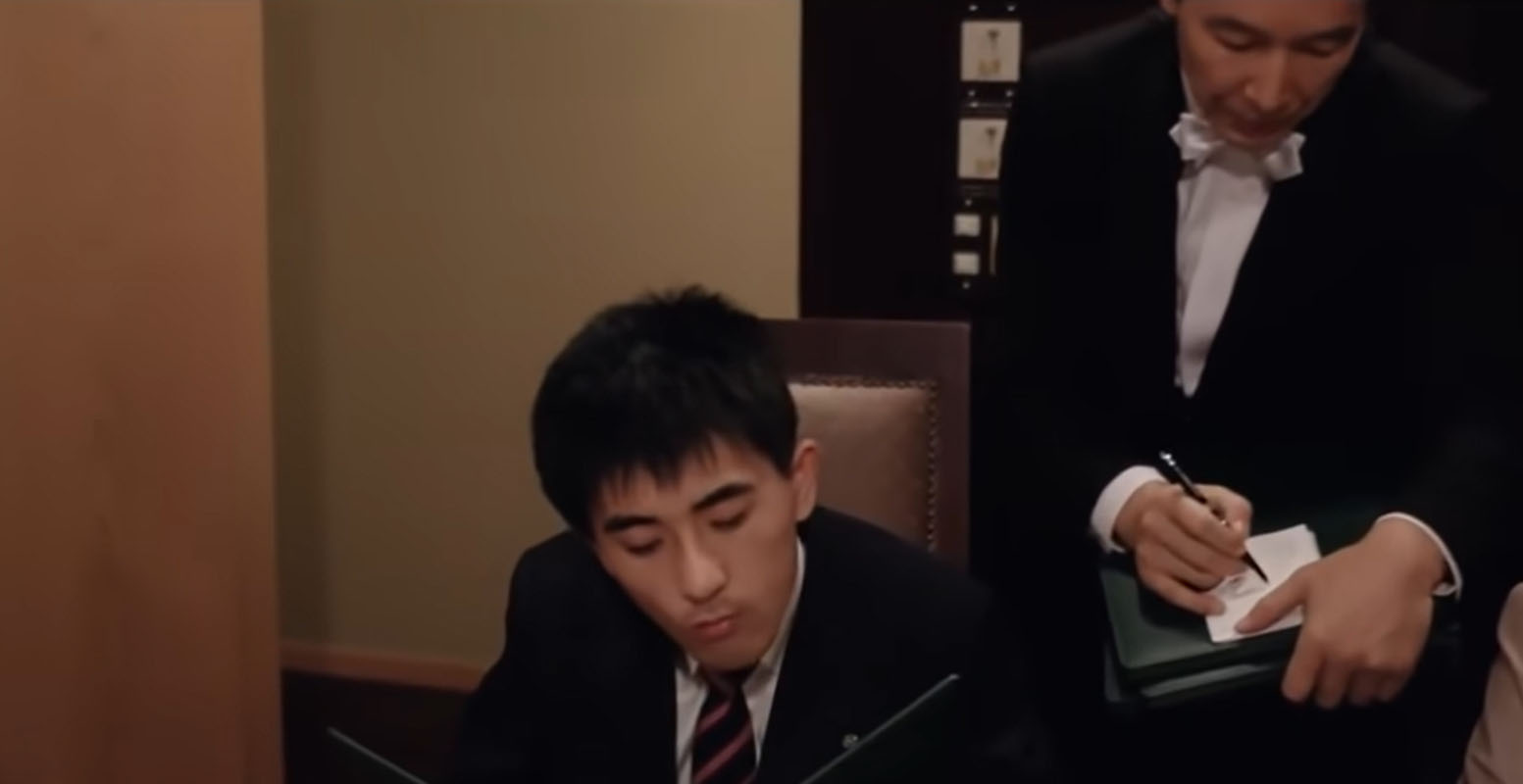 Man studying a menu in front of the waiter ready to take his order pen in hand.