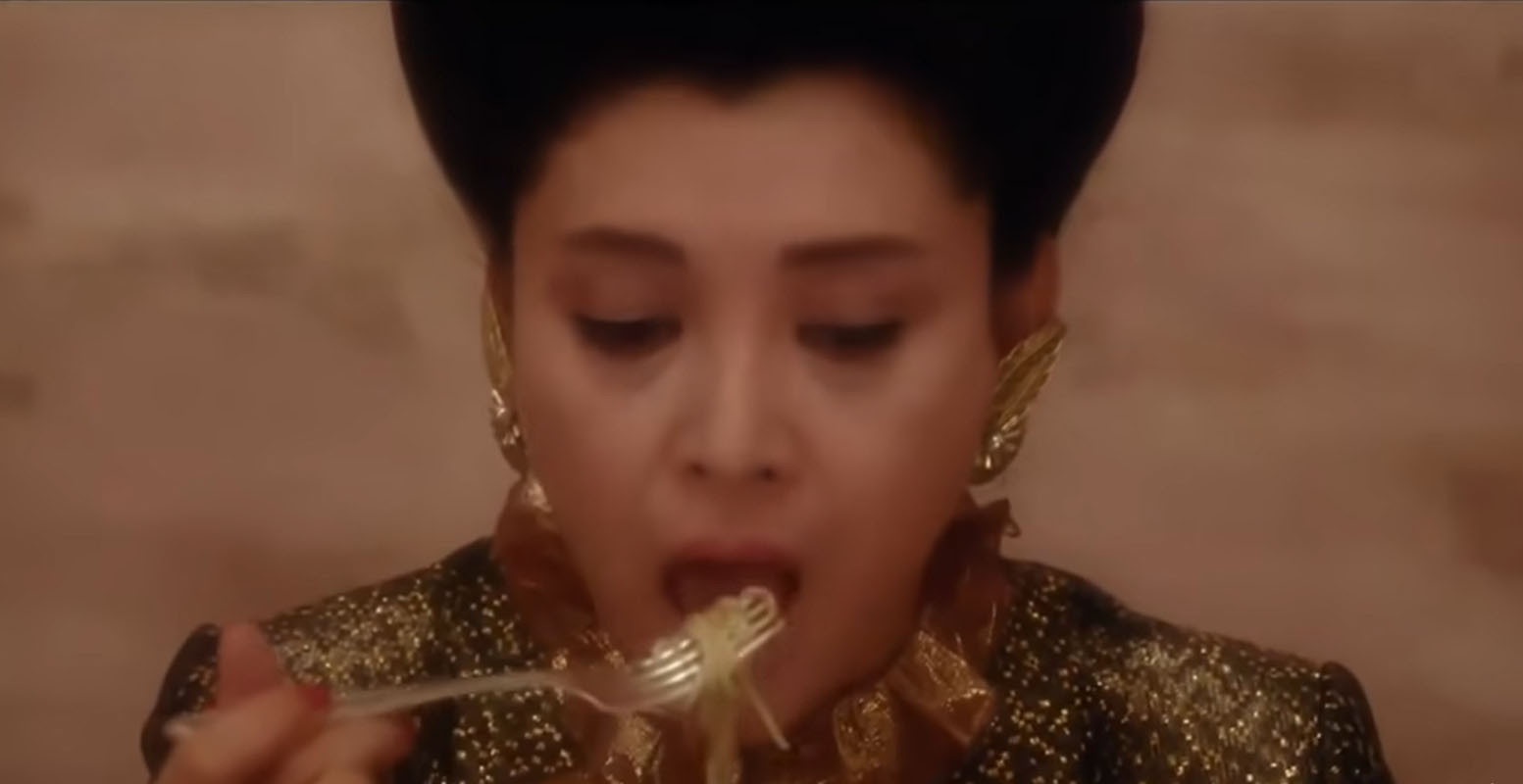 Woman eating spaghetti with a fork and no sauce.